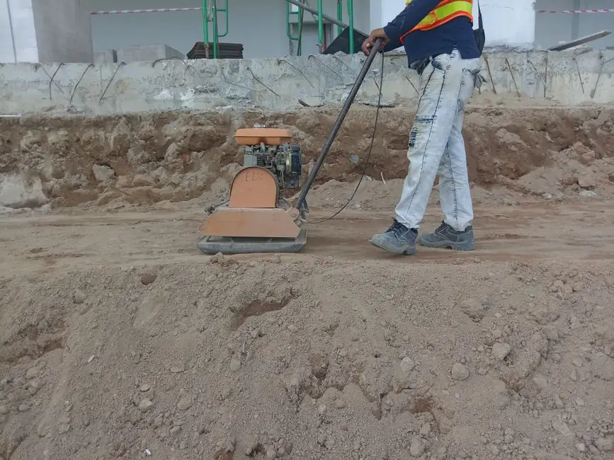A construction worker using a soil compactor outdoors for groundwork.